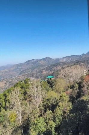 A mountainous landscape with a building with a green roof. - Hotel The Waypoint Inn (Shimla)
