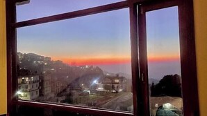 A window with a view of a cityscape at dusk. - Hotel The Waypoint Inn (Shimla)