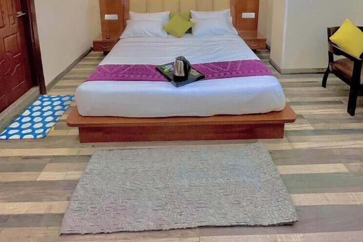 A neatly arranged hotel room with a large bed, a ceiling fan, and a small seating area with a chair and a table.