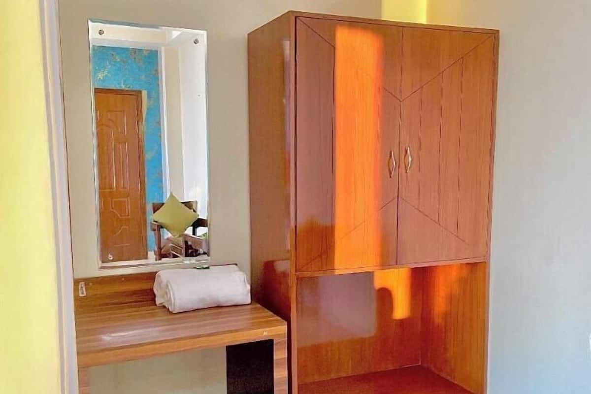 A room with a wooden wardrobe, a bench, and a mirror.
