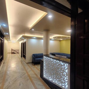 A hotel lobby with a reception desk, seating area, and a hallway leading to other rooms. - Hotel The Waypoint Inn (Shimla)