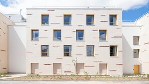 Ένα σύγχρονο, πολυώροφο κτίριο με λευκή πρόσοψη και παράθυρα τοποθετημένα σε τακτά διαστήματα.