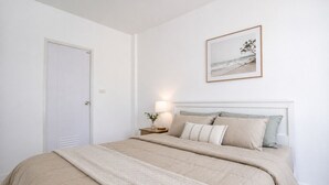 Un dormitorio con cama, mesita de noche, lámpara y un cuadro en la pared.