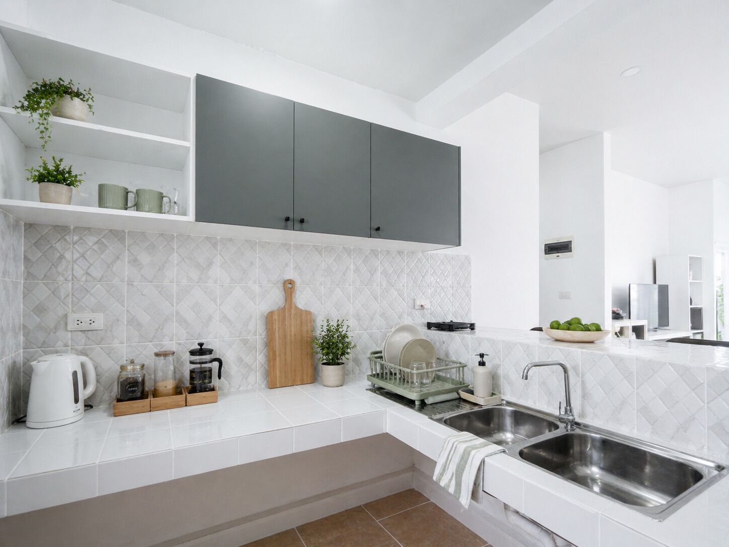 A modern kitchen with white countertops, grey cabinets, and a tiled backsplash.