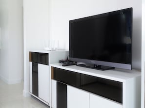 Una sala de estar moderna con un televisor de pantalla plana sobre un mueble blanco.