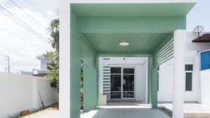 Un edificio moderno con entrada verde y fachada blanca.