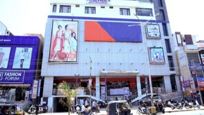 A hotel named 'Hotel Sarayu' with a prominent sign, a large billboard, and a 'Fashion Forum' building adjacent to it. - Hotel Sarayu Hassan (Hassan)