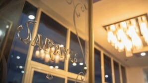 A close-up of a glass window with the word "SARA" reflected in it. - Hotel Sarayu Hassan (Hassan)