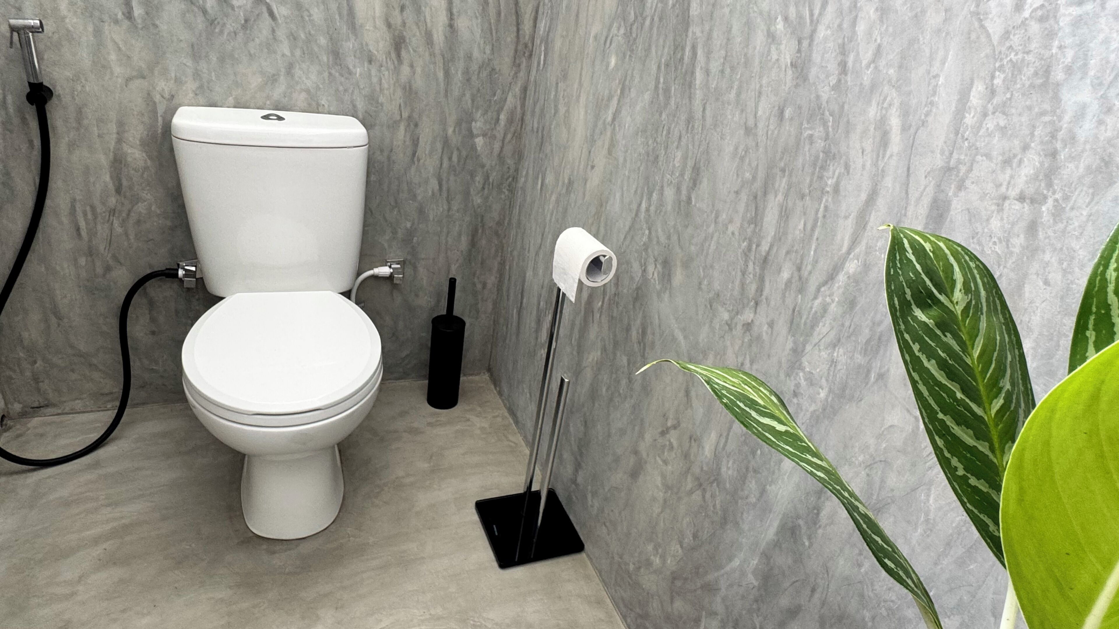 Ein modernes Badezimmer mit Toilette, Bidet und Toilettenpapierhalterung.