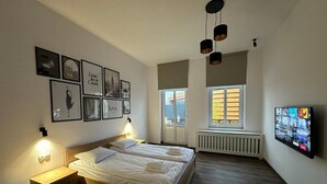 Makuuhuoneessa on suuri sänky, yöpöydät, televisio ja seinällä on kehystettyjä tauluja.
