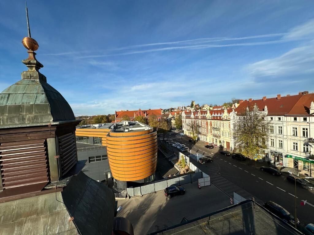 En stadsbild med historiska byggnader, en framträdande orange, cylindrisk konstruktion och en kupolbyggnad med en spir.