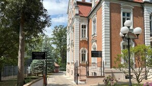 A historic building with a brick facade, a gated entrance, and a sign indicating it is NYSA River Apartments. - Nysa River Apartments (Zgorzelec)