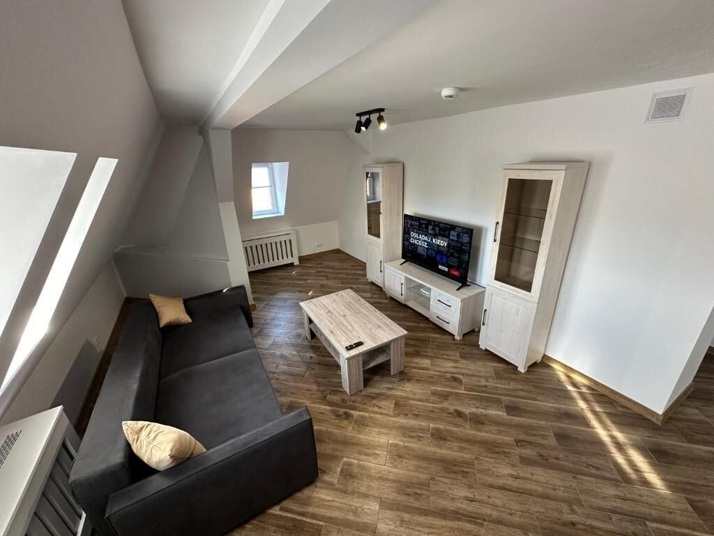 A modern living room with a black sofa, a wooden coffee table, and a TV.