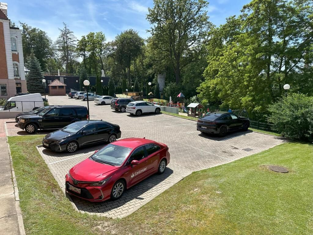 Un estacionamiento con varios coches, incluyendo un sedán rojo y una camioneta blanca.