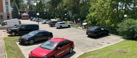 A parking lot with several cars, including a red sedan and a white van.