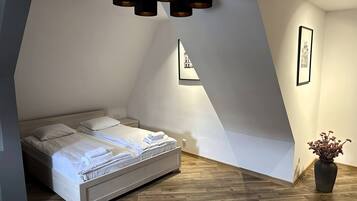Un dormitorio con cama, mesita de noche, lámpara de pared e imagen enmarco.