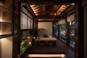 Un comedor tradicional japonés con una mesa baja, sillas y vistas al exterior a través de amplios ventanales.