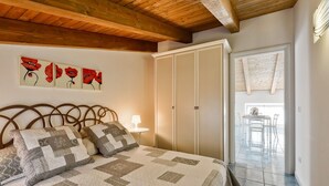A bedroom with a bed, a nightstand, a lamp, a wardrobe, and a view of an outdoor patio. - 2 bedroom stunning apartment in Agropoli (Agropoli)
