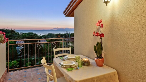 A balcony with a table set for dining, overlooking a scenic view. - 2 bedroom stunning apartment in Agropoli (Agropoli)