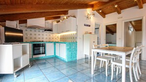 A kitchen with a tiled backsplash, white cabinets, a wooden ceiling, and a dining area with a table and chairs. - 2 bedroom stunning apartment in Agropoli (Agropoli)