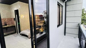 A modern apartment with a glass door leading to a balcony, a kitchen area with a brick backsplash, and a bed with a patterned bedspread. - Casa Karina (Lucena)