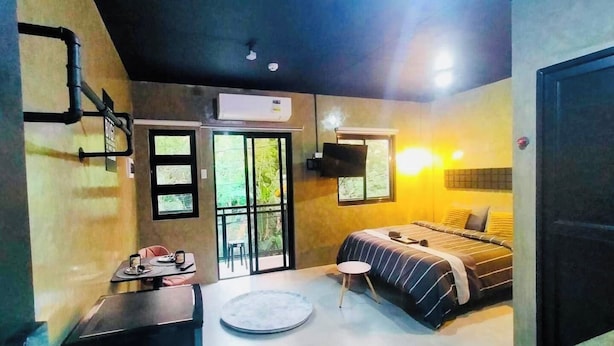 A modern bedroom with a bed, a small table, a round seating area, and a door leading to a balcony. - Casa Karina (Lucena)
