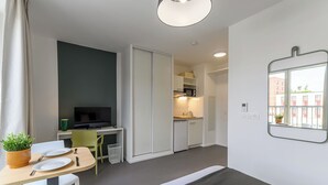 A compact living space with a dining area, kitchenette, and a TV. - Student Factory Paris - Universeine  (Saint-Denis)