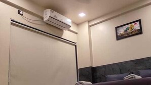 Una habitación de hotel con cama, ventilador de techo, aire acondicionado y armario.