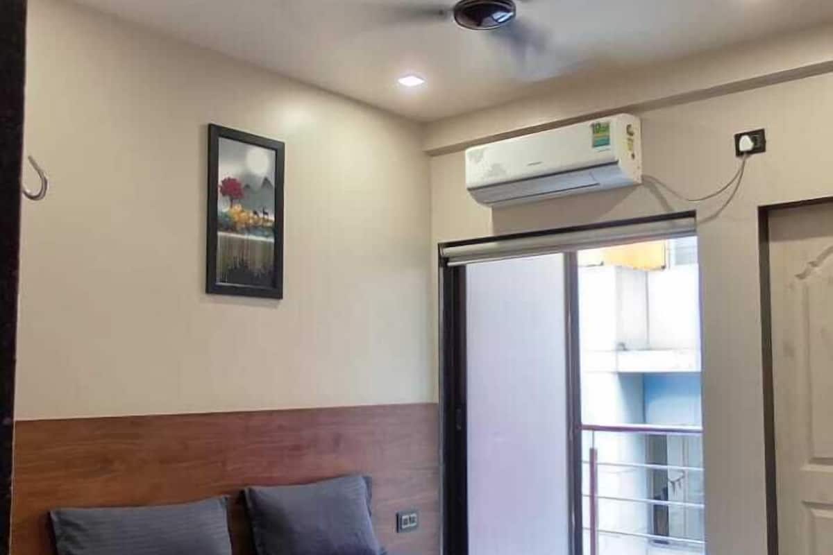 Ein Schlafzimmer mit Bett, Deckenventilator, Klimaanlage und Blick ins Freie.