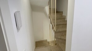 Un couloir étroit avec un escalier menant à un palier.