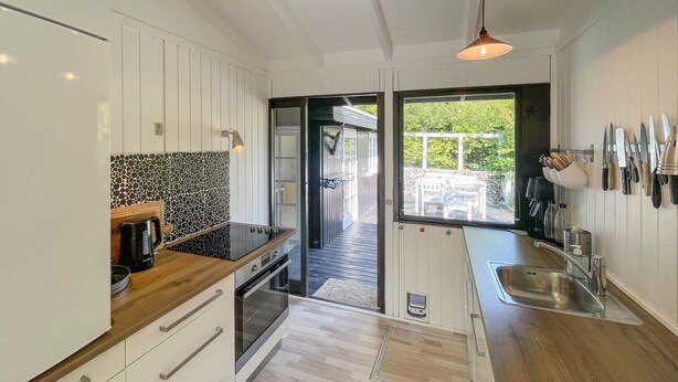 Eine moderne Küche mit weißen Schränken, einer schwarzen Küchenzeile, Holz Arbeitsplatten und einem eingebauten Backofen.