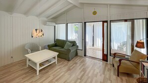 Ein geräumiger Wohnbereich mit einem weißen Tisch, einem grünen Sofa und einem Korbstuhl.