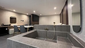 A modern bathroom with a built-in shower, a vanity with a mirror, and a seating area with chairs. - Suwon Hound Hotel (Suwon)