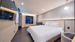 A modern hotel room with a large bed, a TV mounted on the wall, and a window with curtains. - Suwon Hound Hotel (Suwon)