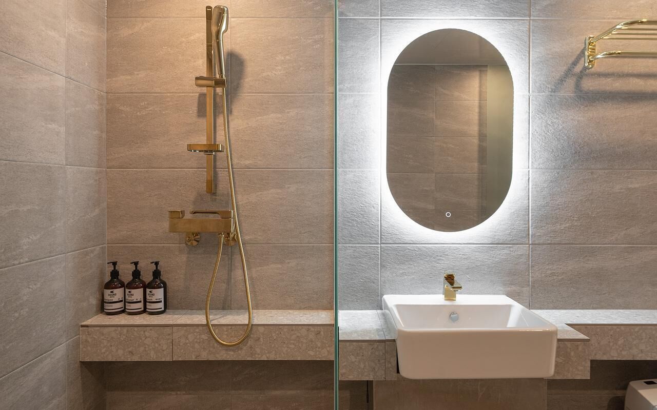 A modern bathroom with a glass-enclosed shower, a white sink, and a mirror.
