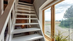 A spiral staircase with wooden steps and white railings, leading to a lofted bedroom with a view of the countryside. - 1 bedroom beautiful apartment in Vallåkra (Vallåkra)