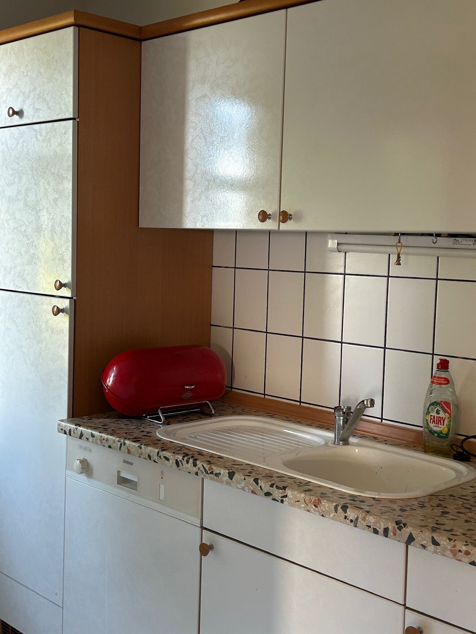A kitchen with white cabinets, a sink, and a red appliance.