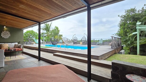 Un espace de vie extérieur moderne comprenant une piscine, une terrasse en bois et des sièges.