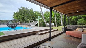 Un espace extérieur abrité comprenant une piscine, une terrasse en bois et des sièges.