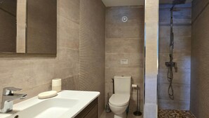 Une salle de bain moderne équipée d’un lavabo, de toilettes et d’une douche.