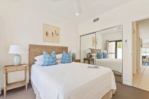A hotel room with a large bed, a nightstand, a mirror, and a painting on the wall. - Noosa Heads Hideaway with Pool & Alfresco Living (Noosa Heads)