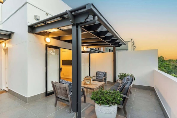 Une terrasse sur le toit, agrémentée d’une pergola, de sièges et de plantes en pot.