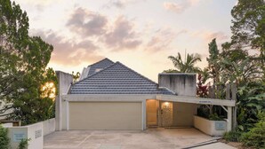A modern two-story house with a garage, surrounded by lush greenery and a clear sky. - Picture Perfect - Panoramic Views, Walk to Beach (Noosa Heads)