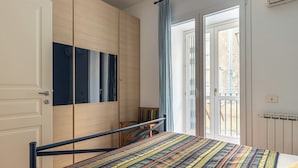 A bedroom with a bed, a wardrobe, a chair, and a window with curtains. - Una Finestra sul Teatro Massimo by Wonderful Italy (Palermo)