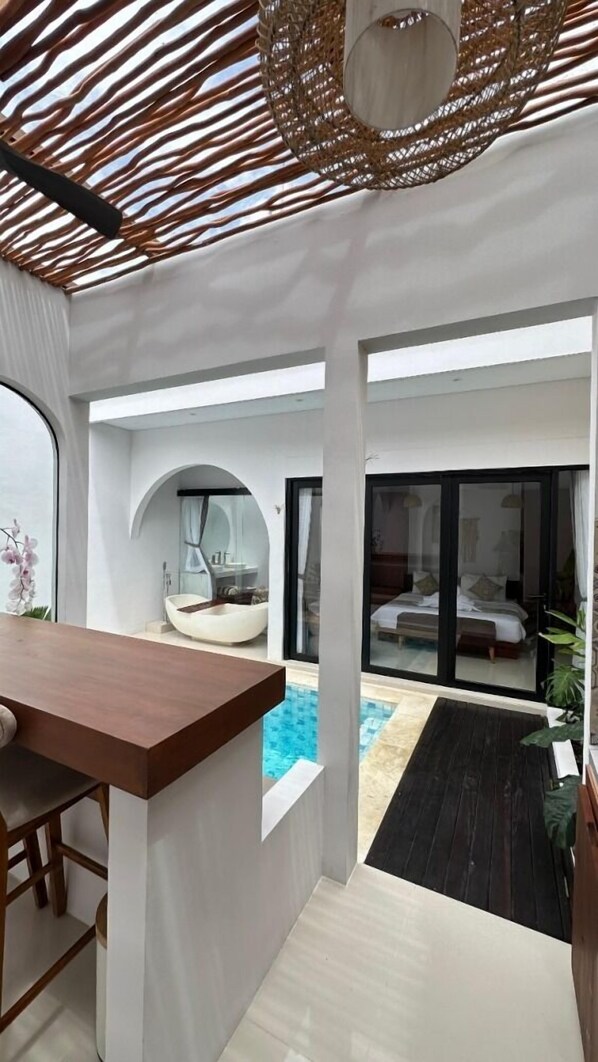 Un intérieur moderne avec une piscine, un bar en bois et un espace salon circulaire.