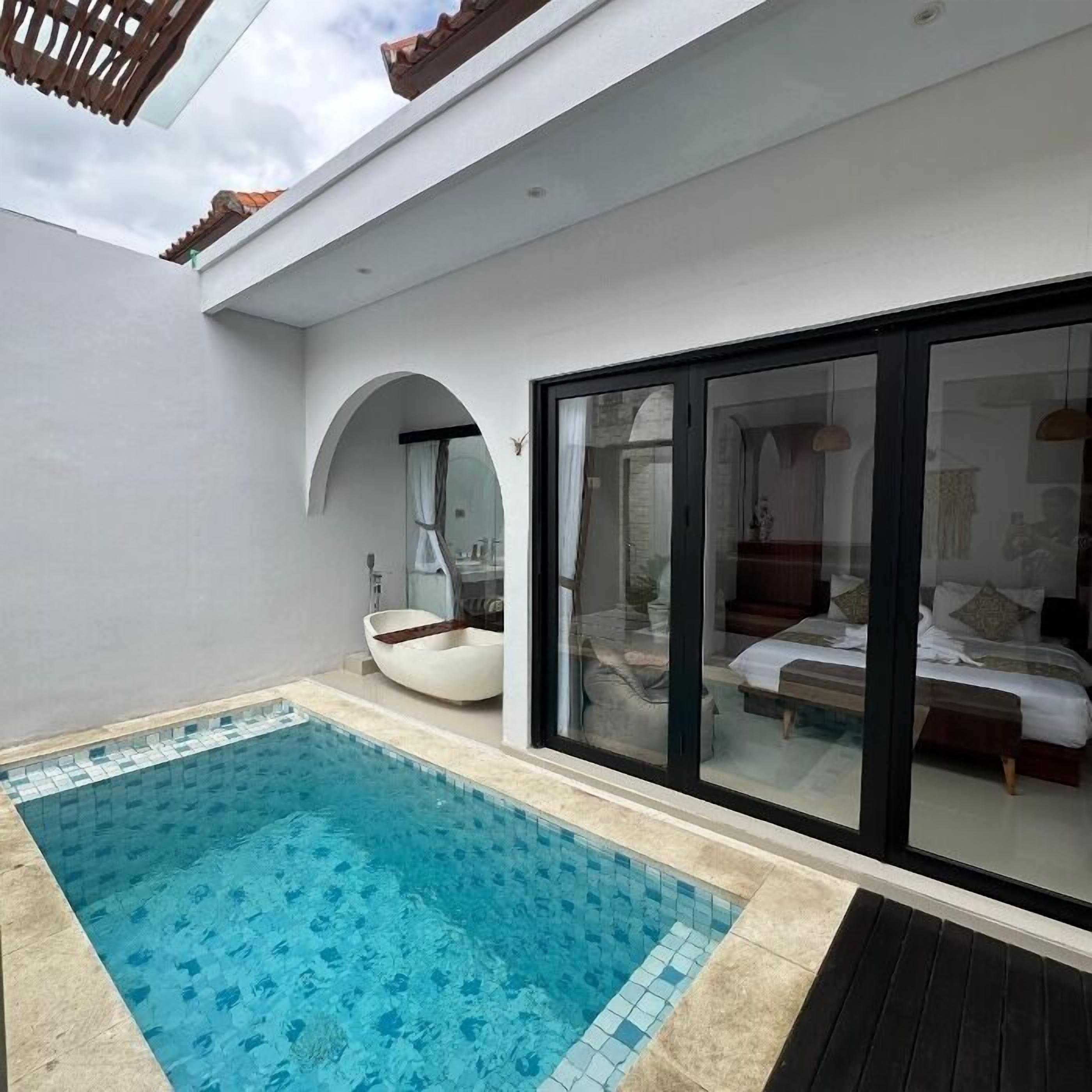 A modern outdoor pool area with a glass-enclosed bedroom visible through the windows.