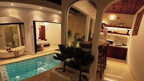A modern bathroom with a bathtub, a shower, and a sink. There is a small pool with a tiled floor. - Maithala Villa (Kuta)