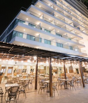 A multi-story hotel with outdoor seating and a covered patio area.