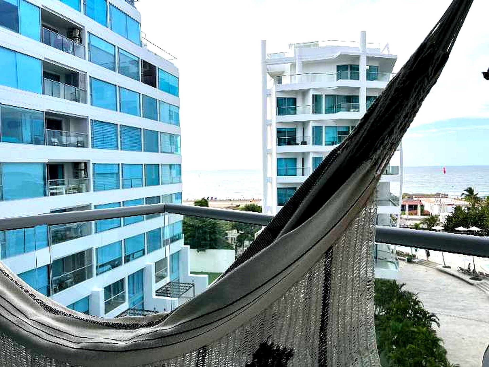 A view of a modern building with multiple floors and balconies, overlooking a body of water.