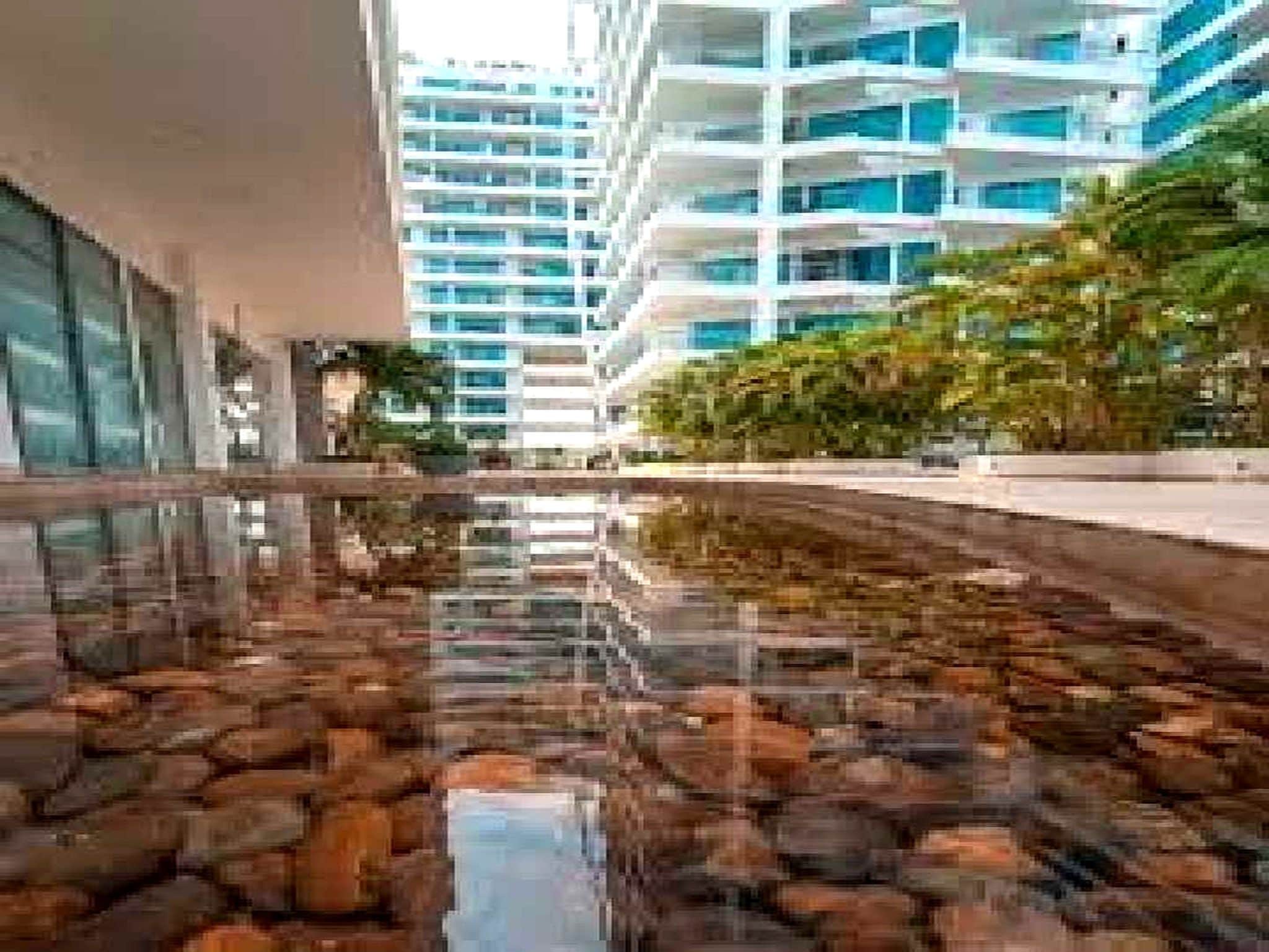 Un edificio moderno con una fuente reflectante en primer plano.